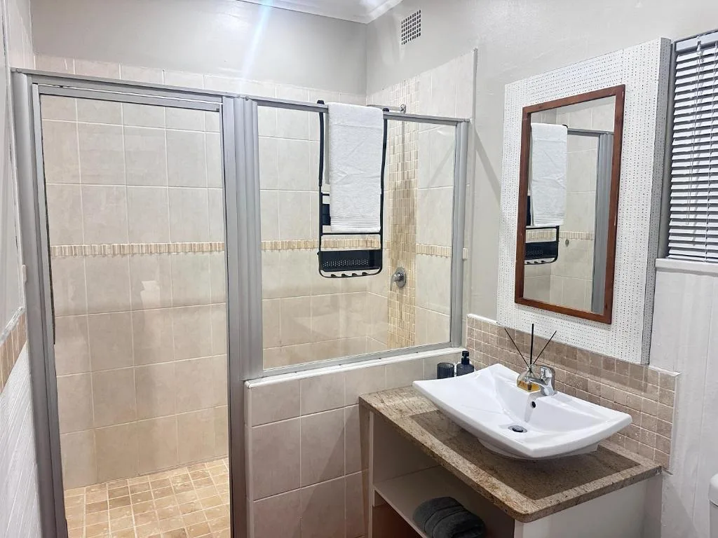 Modern bathroom with shower cubicle, white sink vanity, and framed mirror