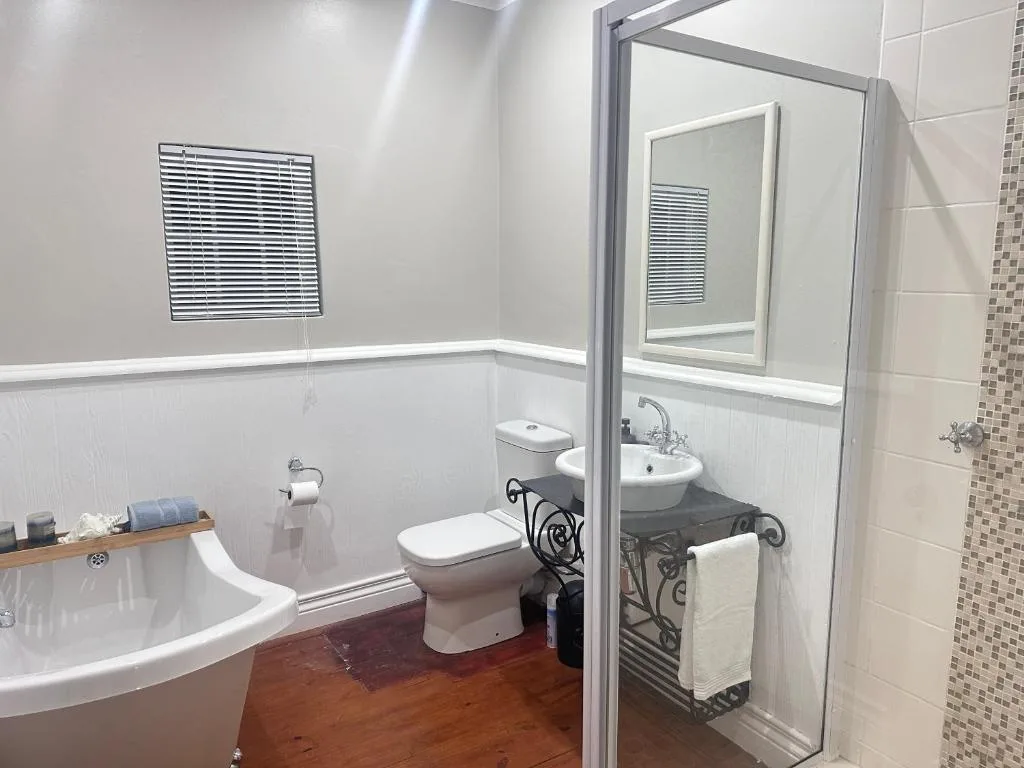 Spacious bathroom with corner bath, toilet, pedestal sink and shower enclosure