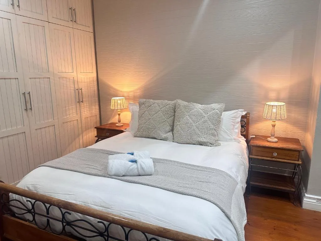 Elegant bedroom with queen bed, gray pillows, warm lighting, wooden wardrobe