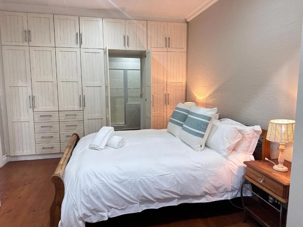 Spacious bedroom with queen bed, white linens, wooden nightstand, and built-in wardrobes