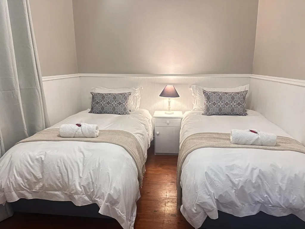 Twin beds with white linens and patterned pillows in bright bedroom