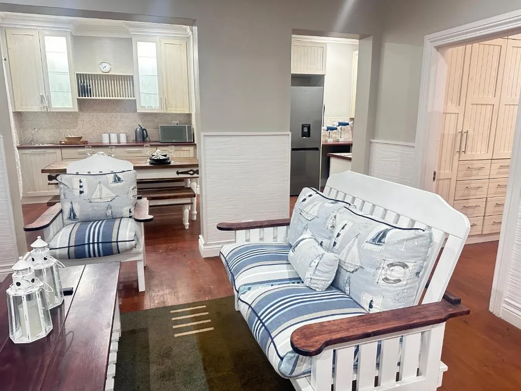 Modern bedroom with two single beds and nautical-themed bedding, adjacent kitchen visible
