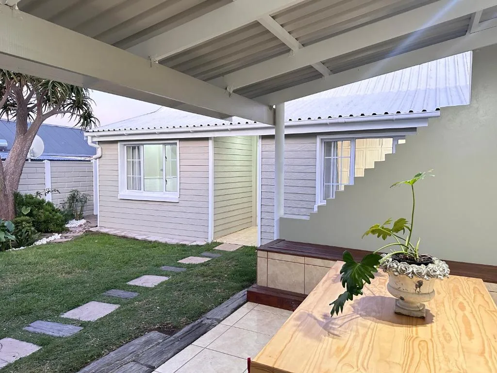 Covered patio with wooden table overlooking manicured garden and cottage
