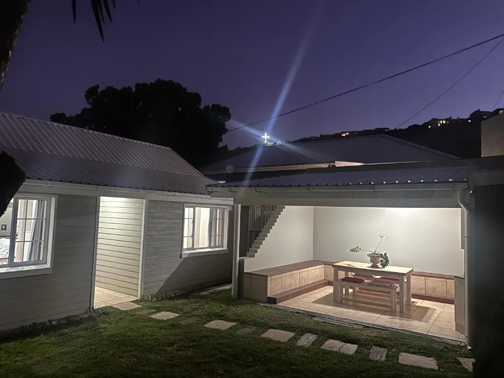 Modern villa exterior at dusk with illuminated covered deck area and manicured lawn