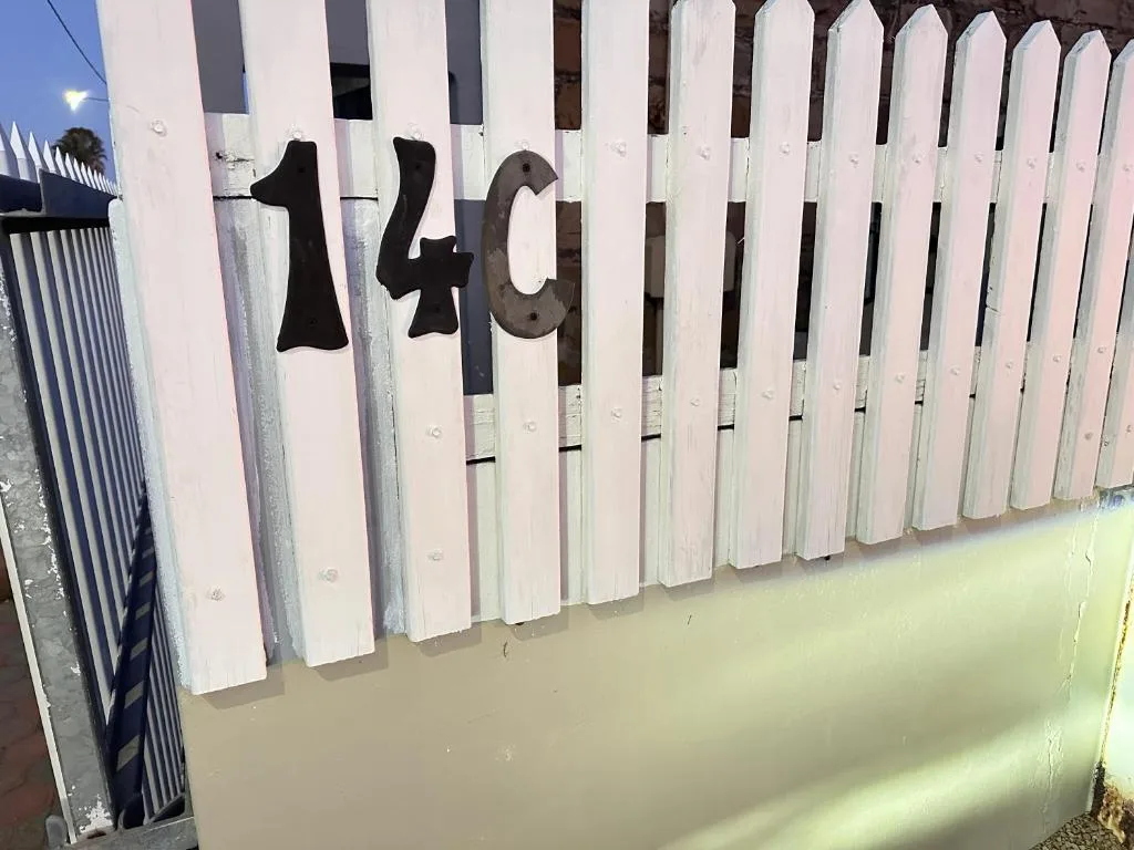 White picket fence with black house number 140 mounted on gate