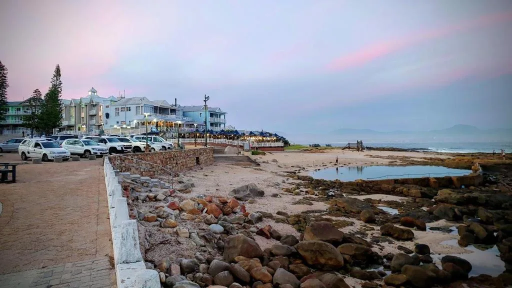 Beachfront villa with parking at sunset, rocky shore visible