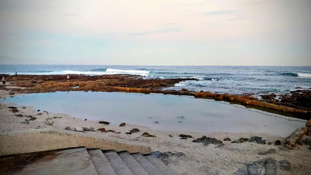 Coastal ocean view with rocky tidal pools and breaking waves at sunset