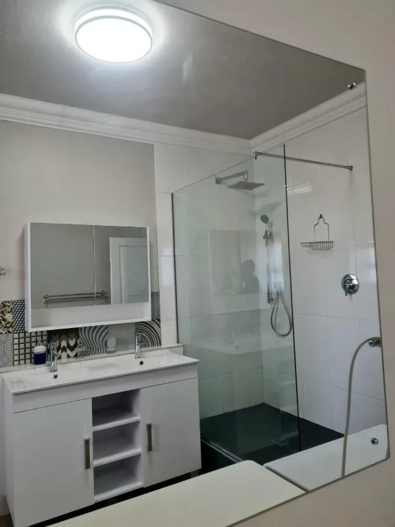 Modern bathroom with vanity, mirror, and enclosed glass shower enclosure