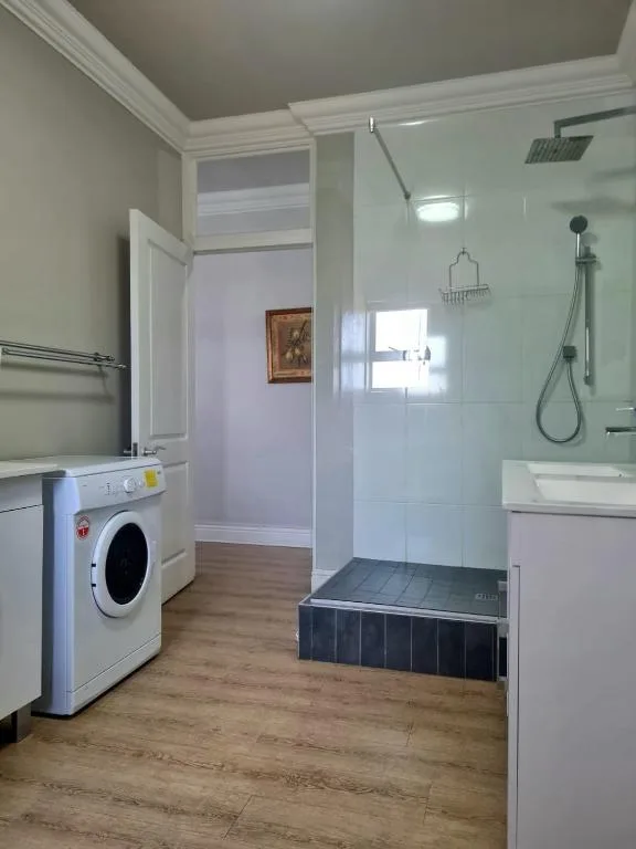 Modern bathroom with walk-in shower, washing machine, and vanity sink