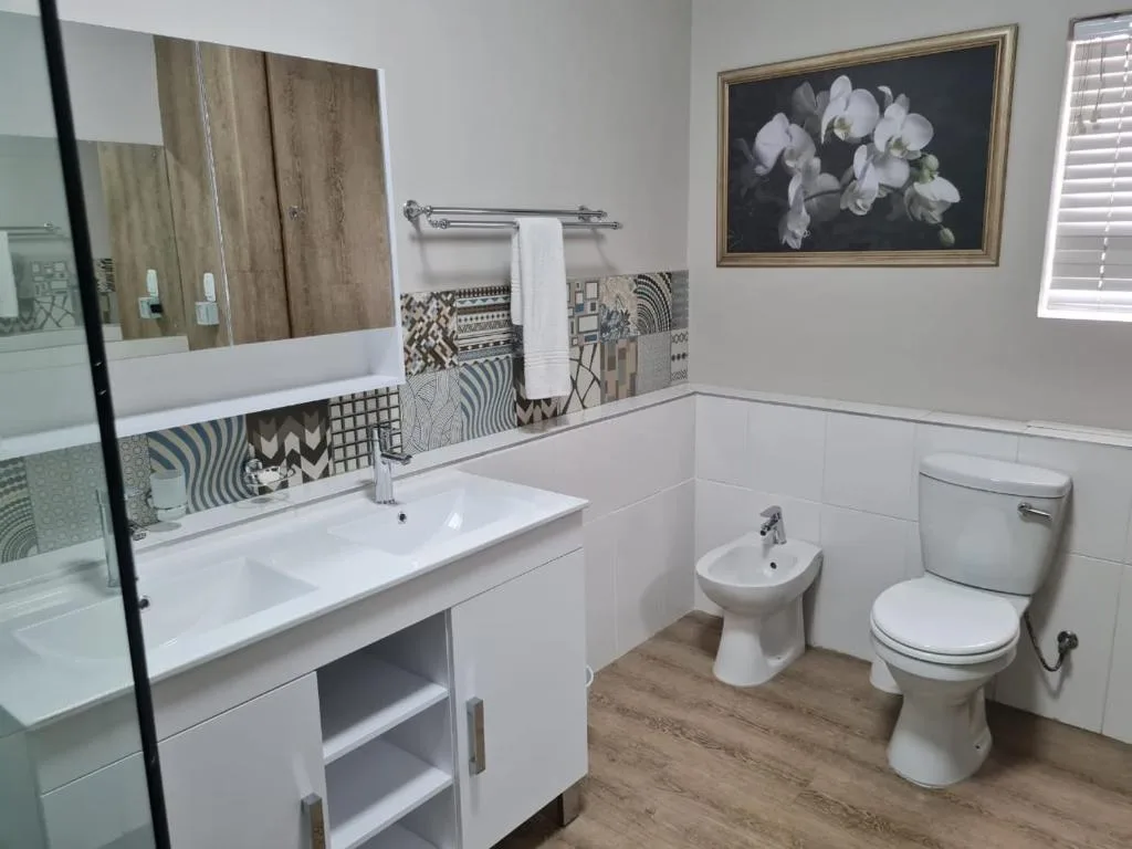 Modern bathroom with vanity, toilet, bidet, and decorative tile backsplash