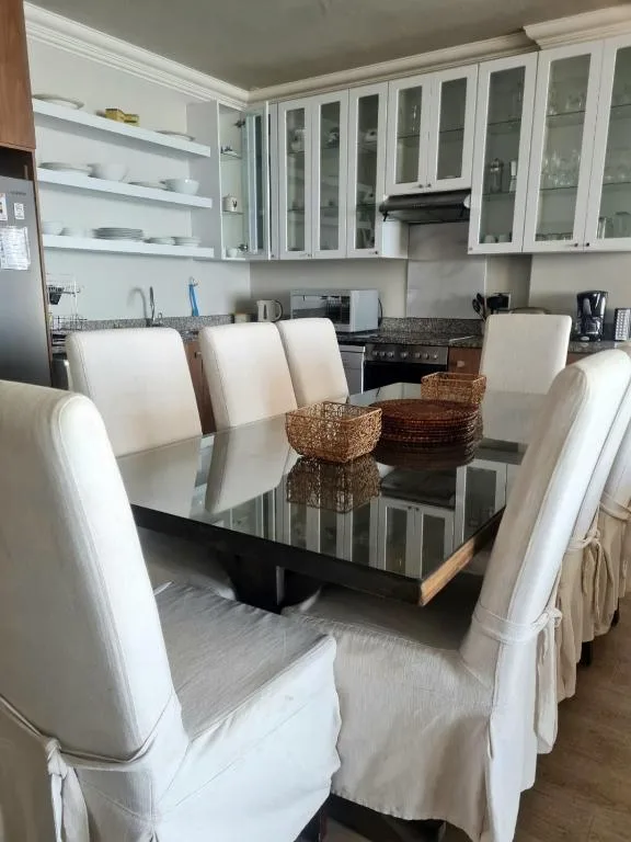 Modern dining table with white chairs in open-plan kitchen area