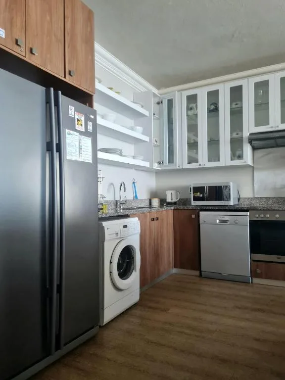 Modern kitchen with stainless steel appliances, wooden cabinetry, and open shelving