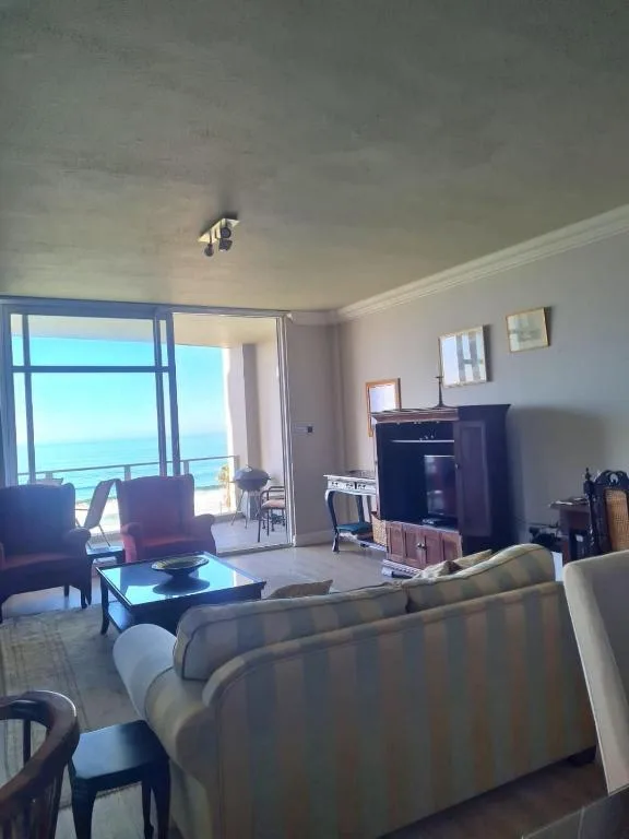Spacious lounge with ocean view through glass doors and modern furnishings