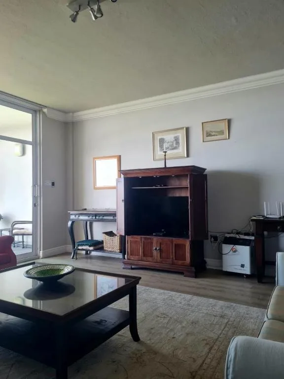 Spacious living room with dark furniture and coastal artwork on walls
