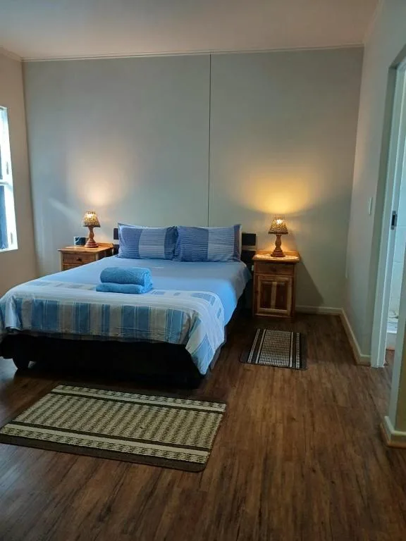 Bright bedroom with queen bed, striped bedding, and warm bedside lamps