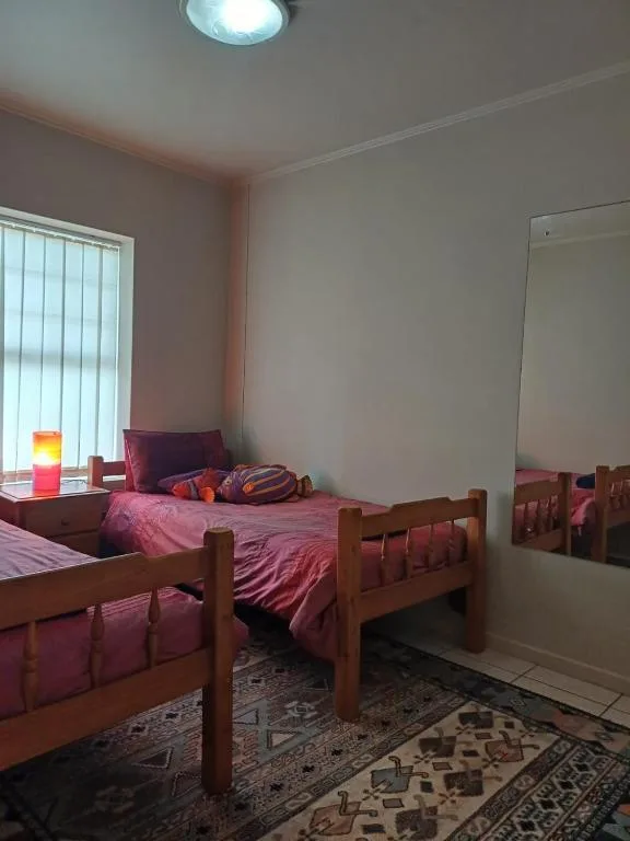 Bedroom with wooden beds, pink bedding, and natural window light