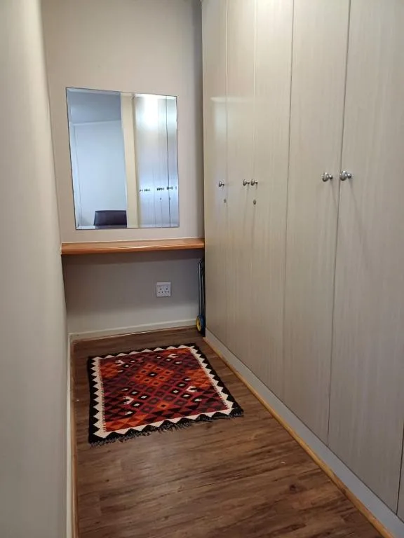 Vanity mirror with wooden shelf and cream wardrobe cabinetry in hallway