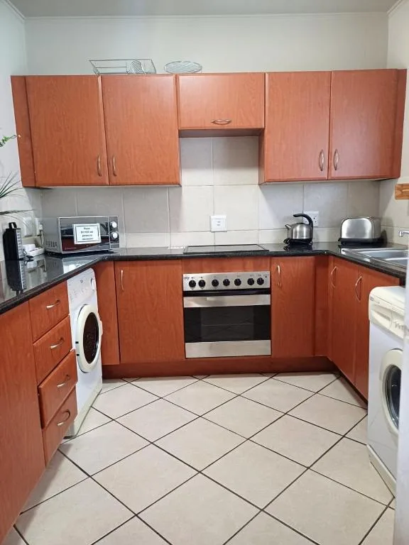 Modern kitchen with wooden cabinetry, stainless steel oven, and tiled flooring