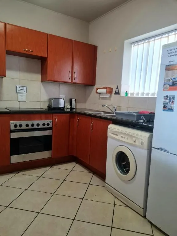 Modern kitchen with red cabinetry, stainless steel stove, and washing machine