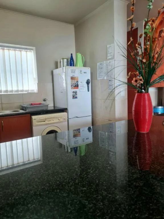 Modern kitchen with white refrigerator, washing machine, and red decorative vase