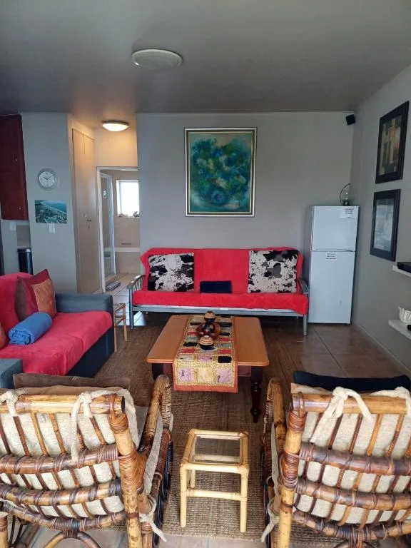 Bright living room with red sofa, wicker chairs, wooden coffee table