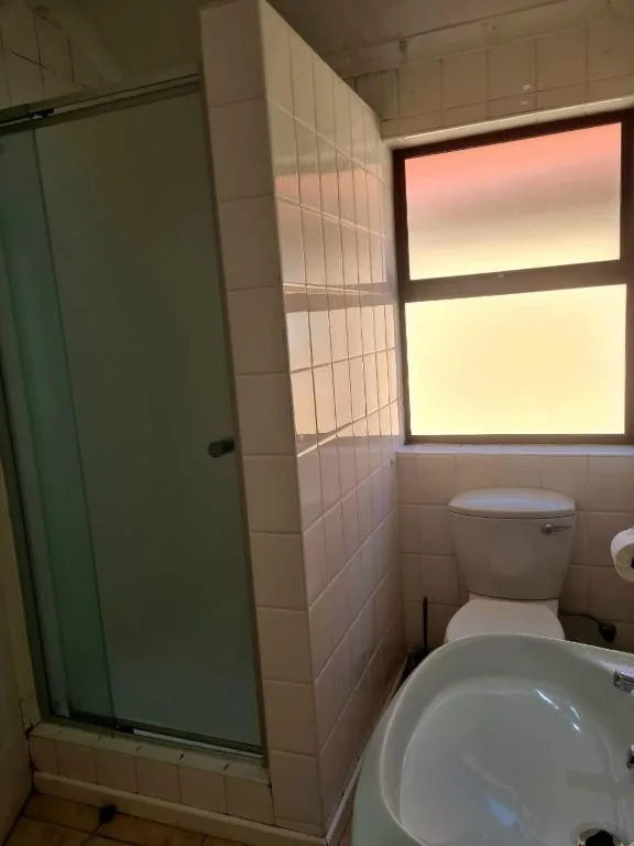 Bathroom with shower enclosure, toilet, basin, and window