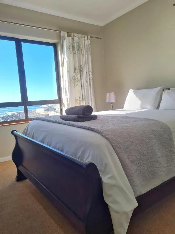 Spacious bedroom with ocean view through large window and coastal landscape