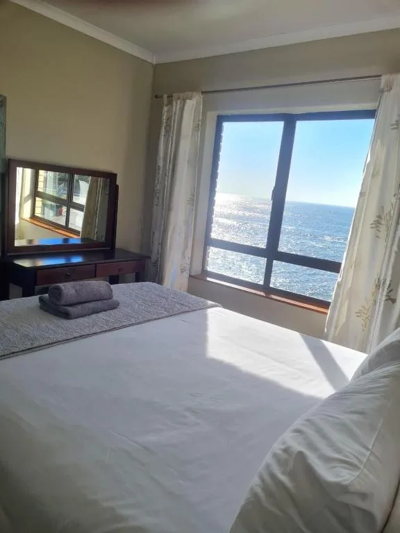 Bright bedroom with ocean view through large windows and coastal landscape
