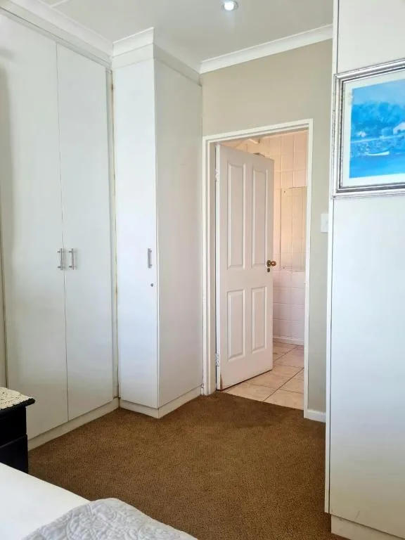 Bright bedroom with built-in wardrobe and view to ensuite bathroom