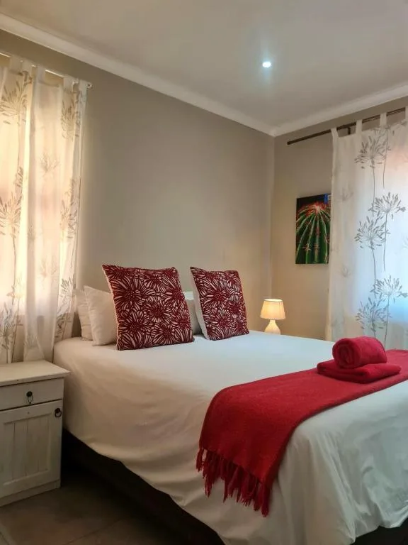 Bright bedroom with queen bed, burgundy accent pillows and throw blanket