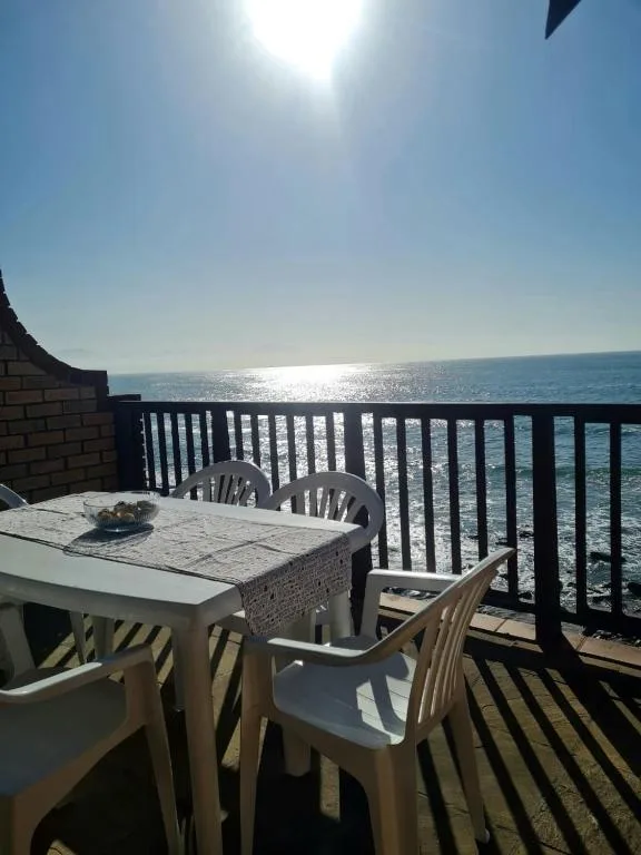 Seaside balcony with dining table overlooking sparkling ocean waters