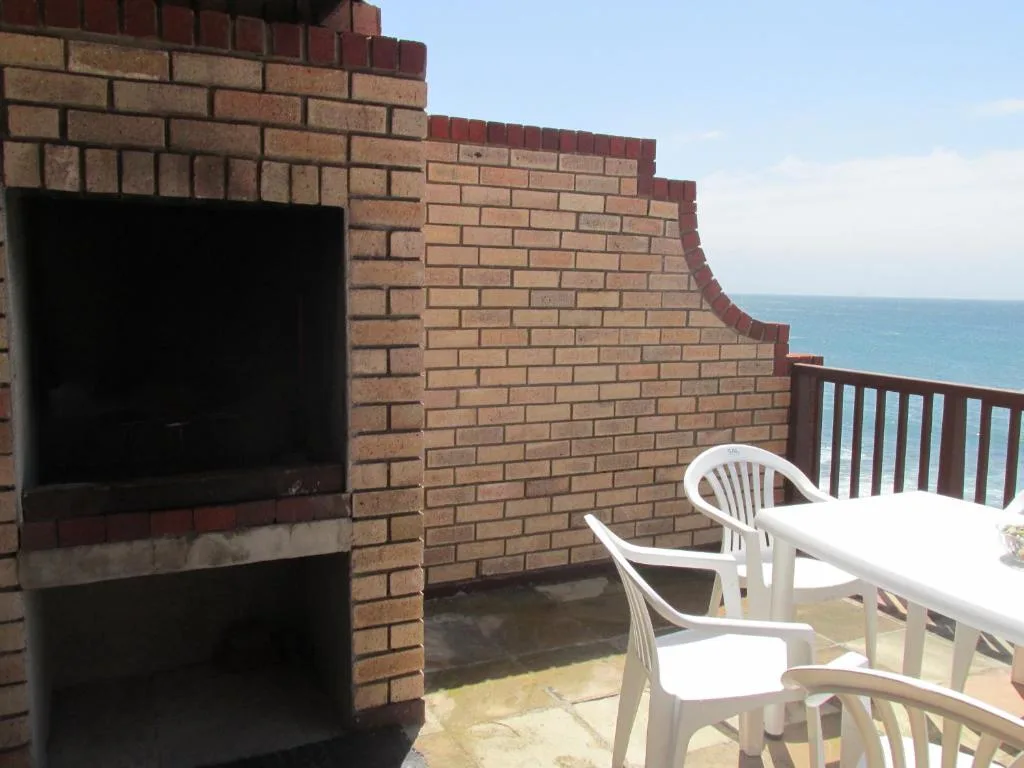 Brick patio with white chairs and ocean view beyond wooden railing
