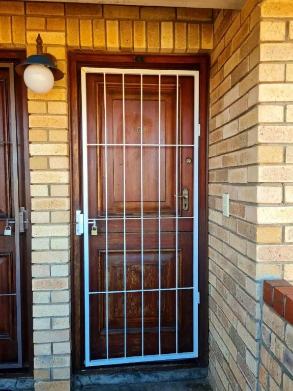 Brick entrance with wooden door and security gate at property
