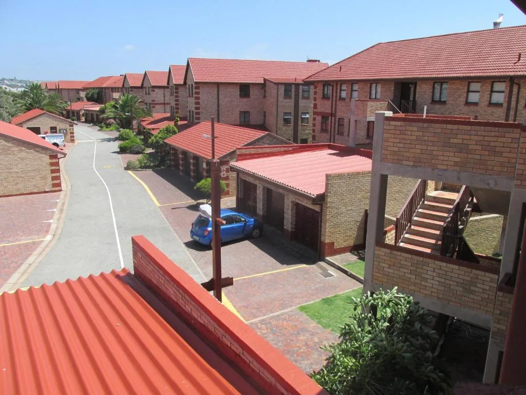Brick residential complex with red roofs and shared courtyard parking area