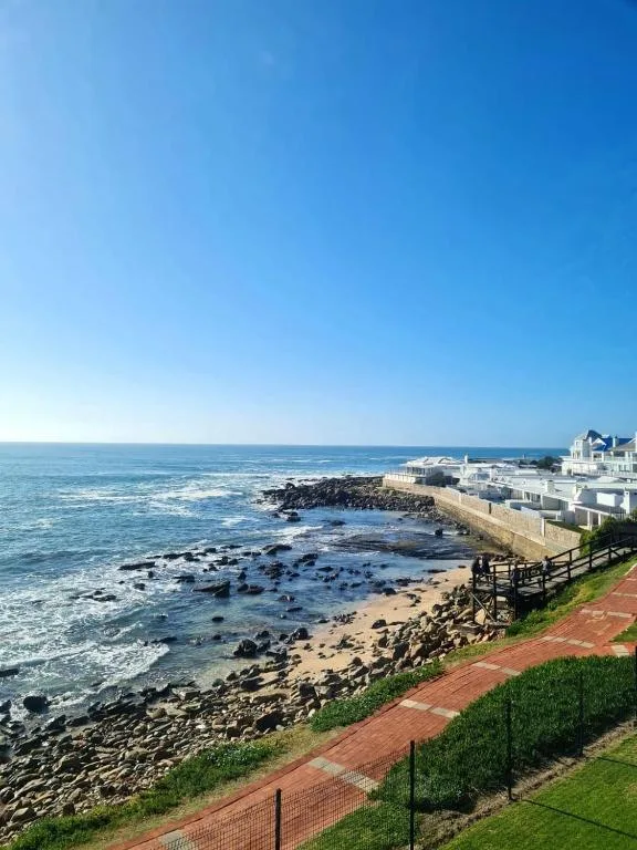 Scenic coastal view with rocky beach, white buildings, and blue ocean horizon