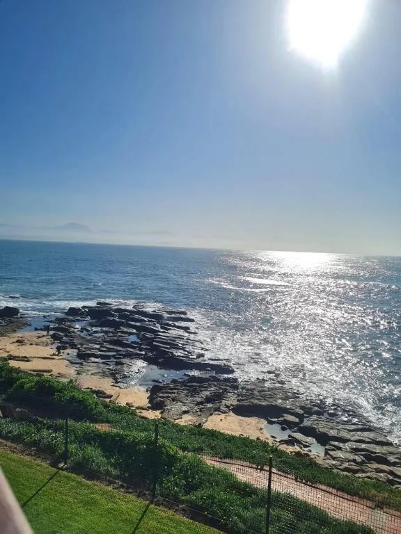 Scenic ocean view with rocky coastline and sparkling sea under clear blue sky