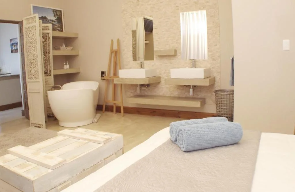 Modern bathroom with freestanding tub, dual vanities, and natural light