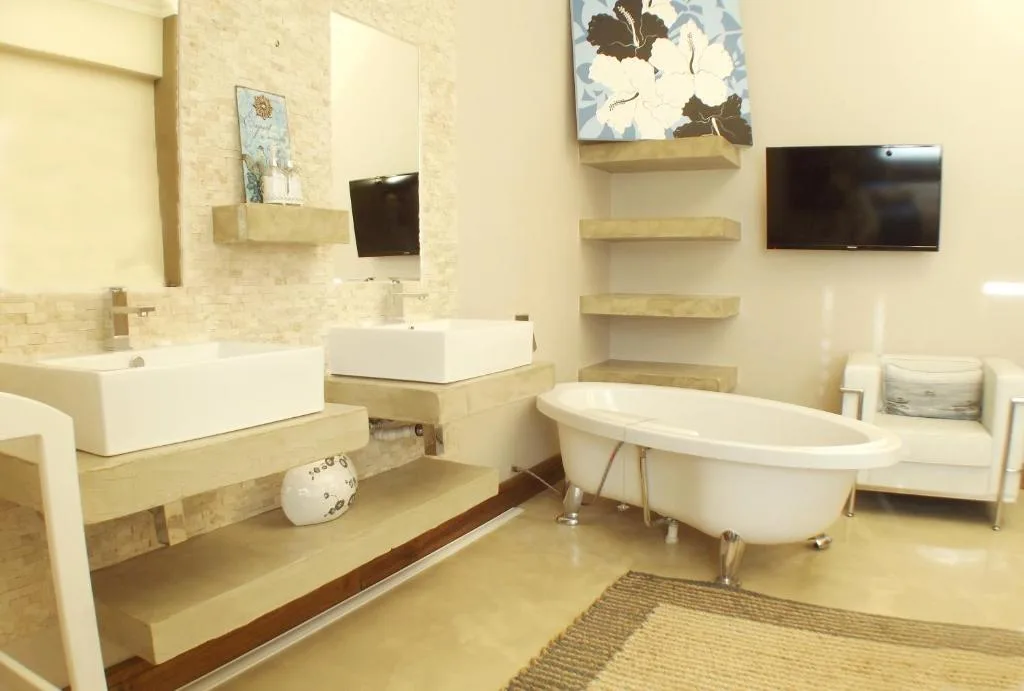 Modern bathroom with dual vanities, soaking tub, and mounted television