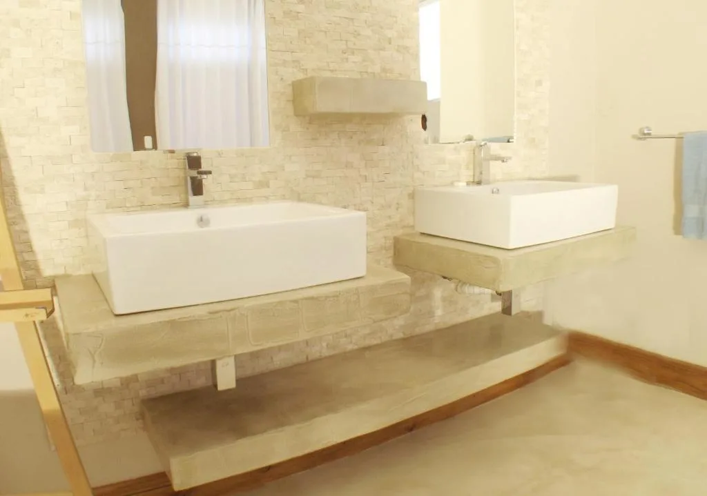 Modern bathroom with dual white vessel sinks and cream tile walls