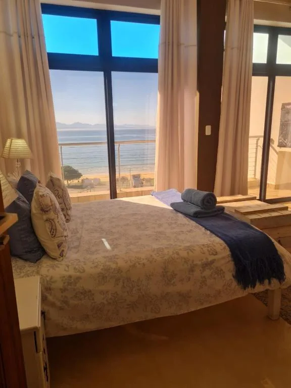 Bedroom with ocean and mountain views through large windows