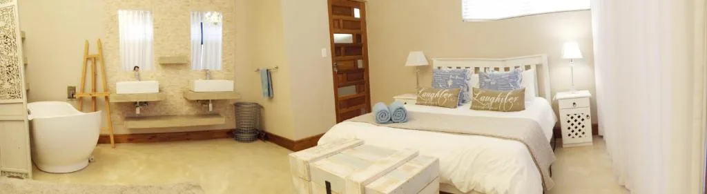 Spacious bedroom with queen bed, ensuite bathroom, and natural light from windows