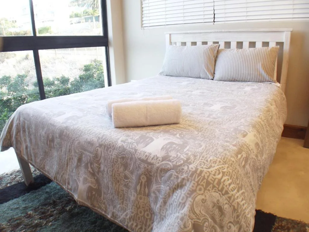 Bright bedroom with queen bed, striped pillows, large windows overlooking greenery