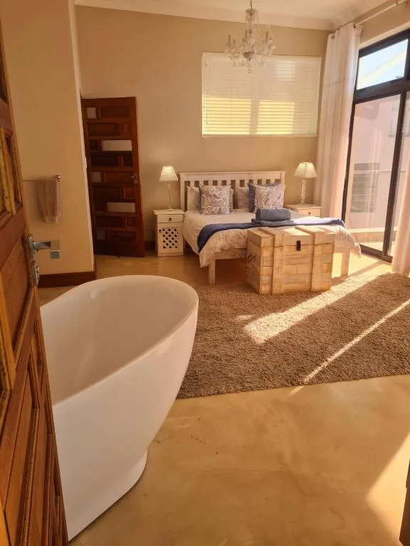 Spacious bedroom with bed, freestanding bath, and natural light from windows