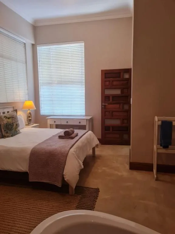 Spacious bedroom with single bed, wooden shelving, and natural light from window