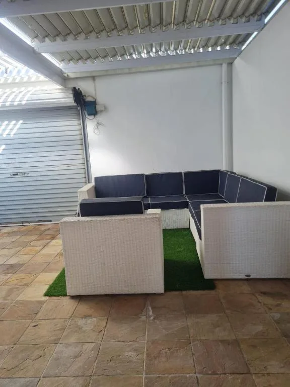 Covered patio with modern outdoor seating and artificial grass flooring
