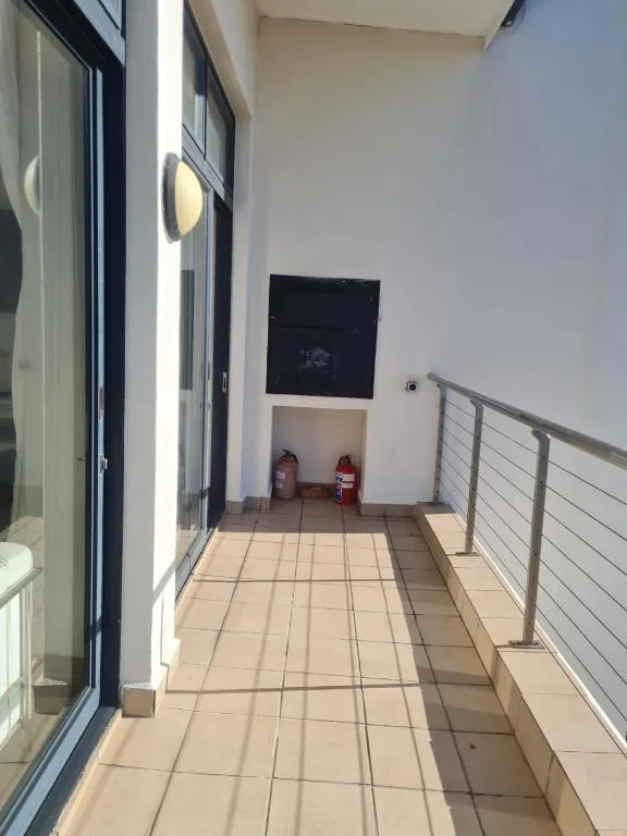 Sunny outdoor balcony with tiled flooring and metal railing
