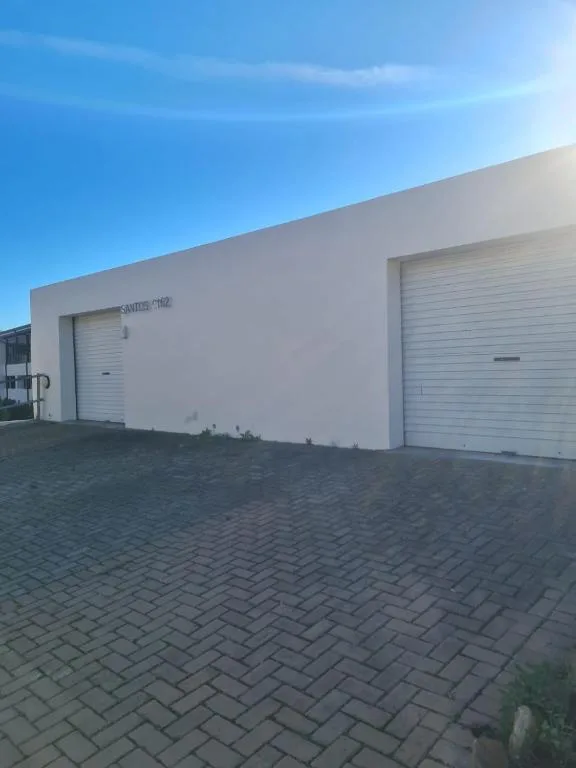 Modern white apartment building facade with roller garage doors and paved driveway