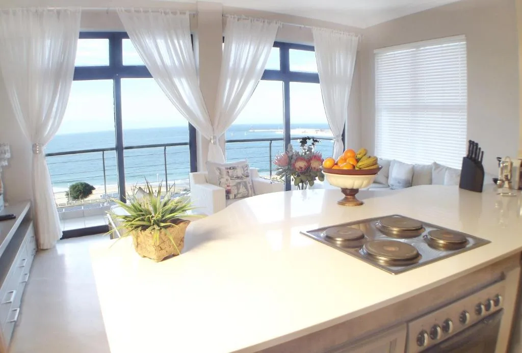 Modern kitchen with ocean views through large windows and coastal scenery