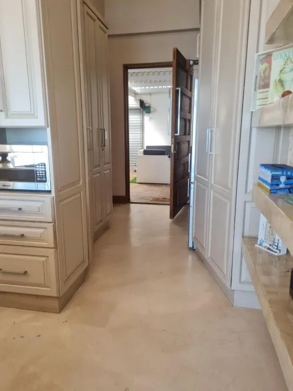 Kitchen hallway with wooden cabinetry, microwave, and open doorway leading to bedroom