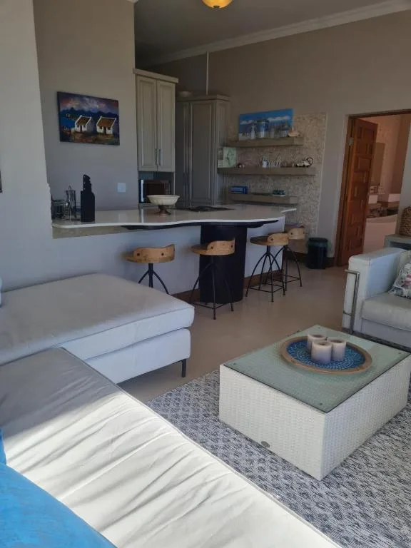 Open-plan lounge with sofa, kitchen counter seating, and modern décor